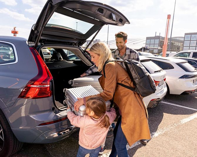 Familie lädt Koffer am Flughafen ins Auto